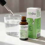 Gotas de ABSlim disueltas en un vaso de agua junto al envase
